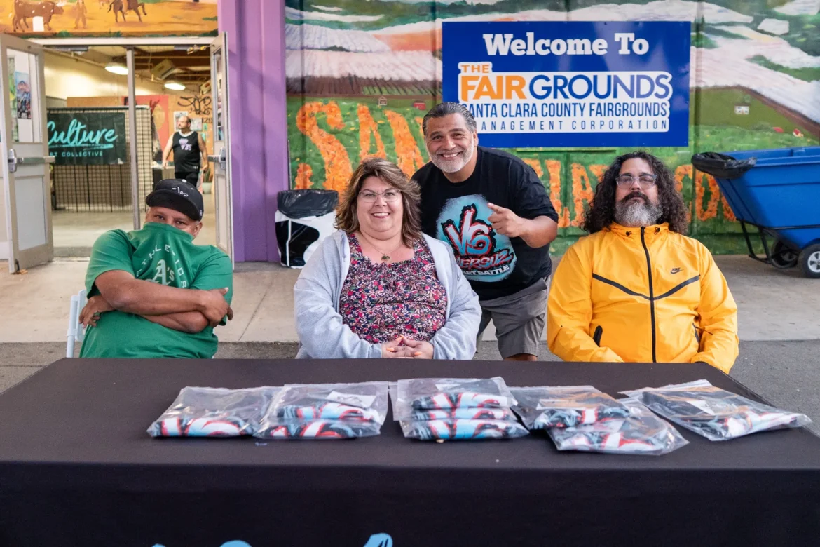 The live art team sits behind their prints at the Fairgrounds welcome sign.