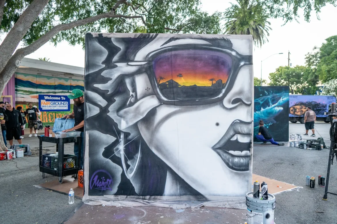 A spray-painted mural of a face in mirrored sunglasses takes shape.