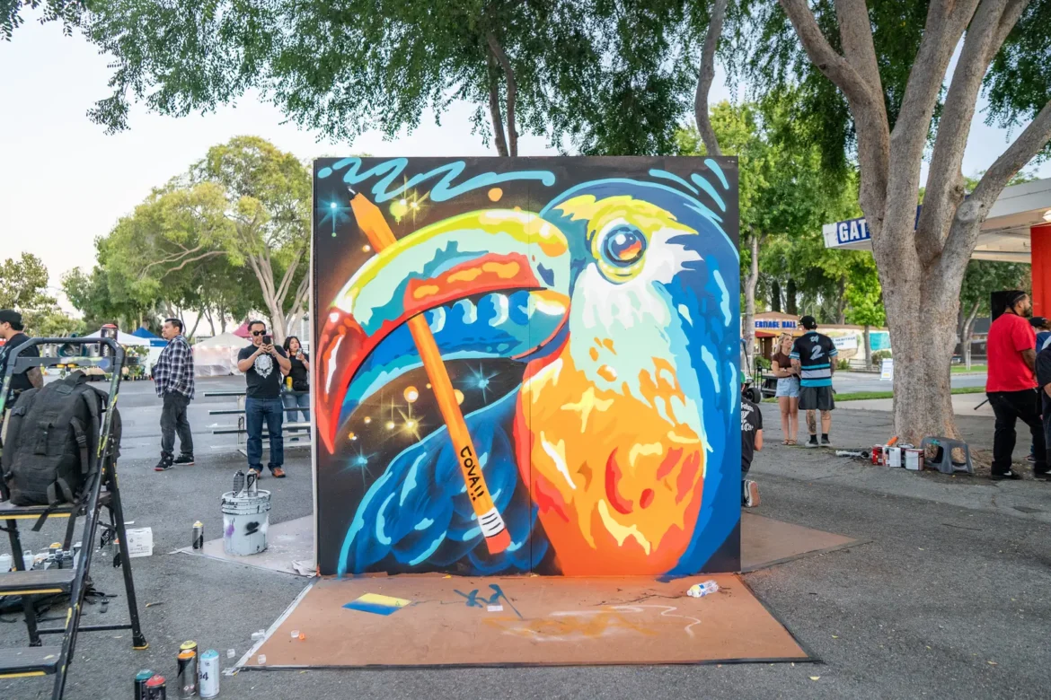 A bright mural of a bird in orange and blue nears completion.