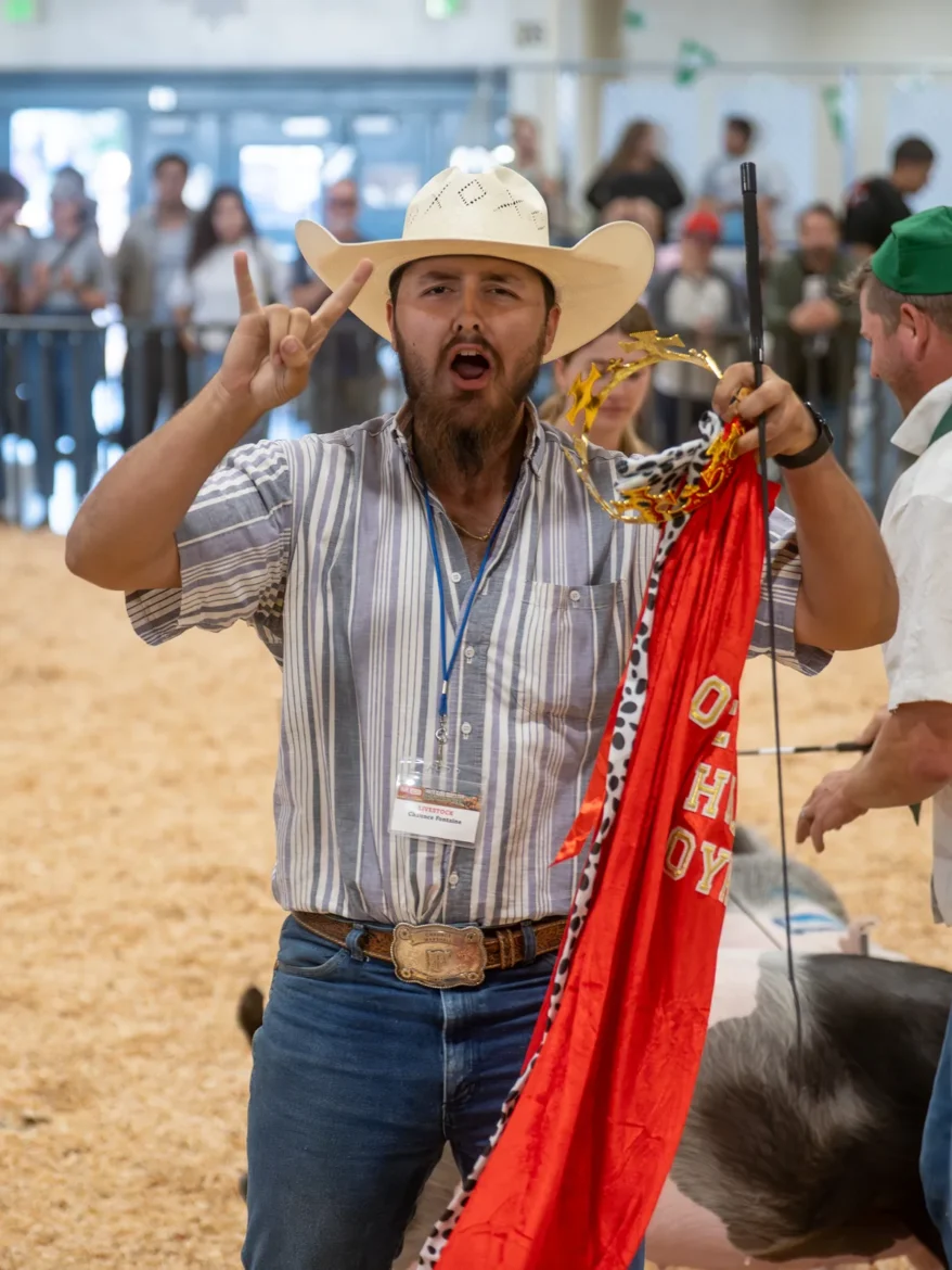 A winning exhibitor holds up his red champion banner.