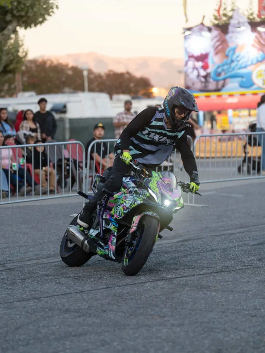 A stunt rider pulls a wheelie in front of the grandstand.