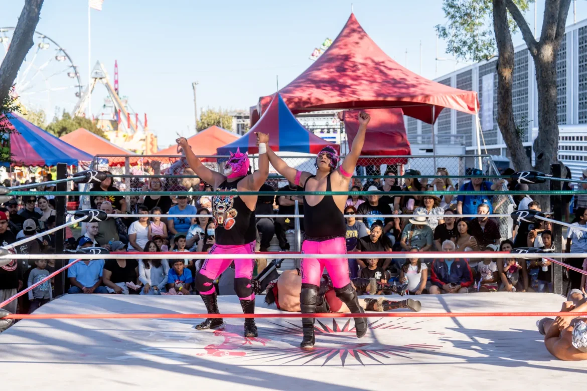 Lucha libre wrestlers grapple in the ring under the lights.