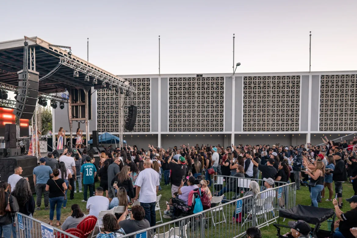 A daytime crowd gathers in front of the main stage.