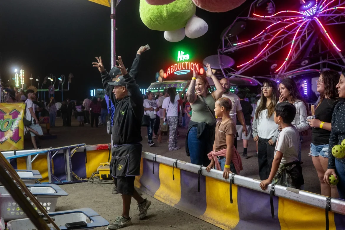 A carnival game glows in neon while players try their luck.