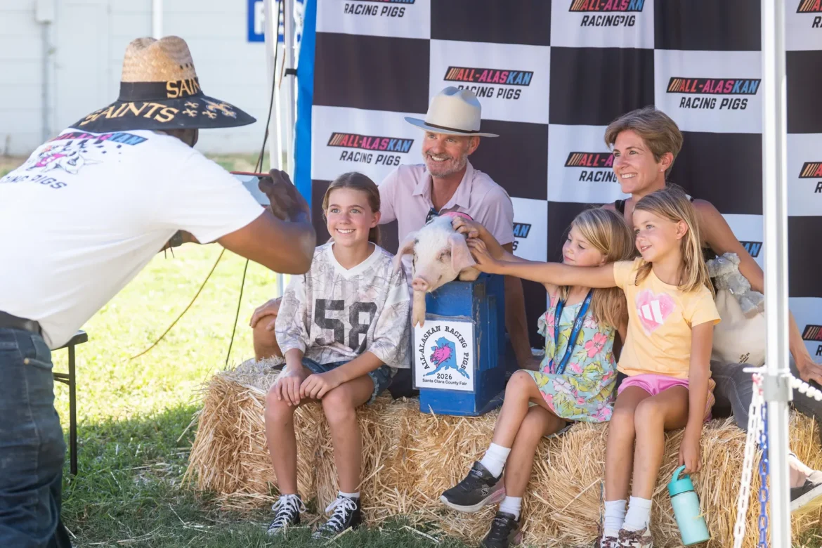 Kids pet a piglet at the Racing Pigs photo backdrop.