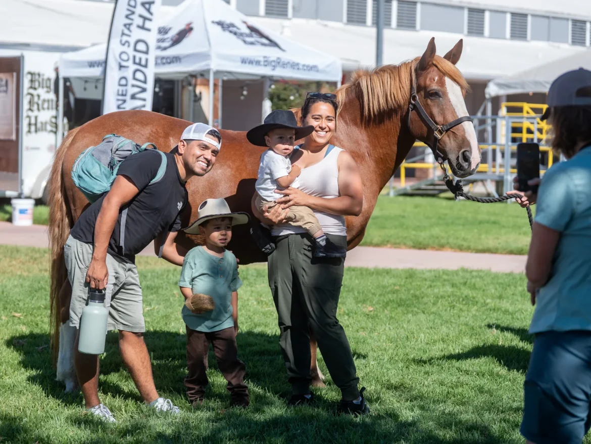 A family meets a horse on the fairgrounds lawn.