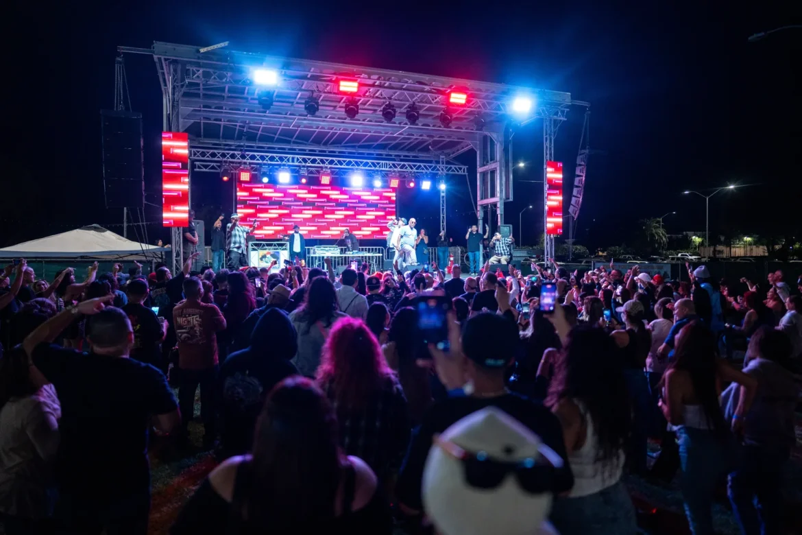 The crowd cheers at a night concert lit in red and blue.