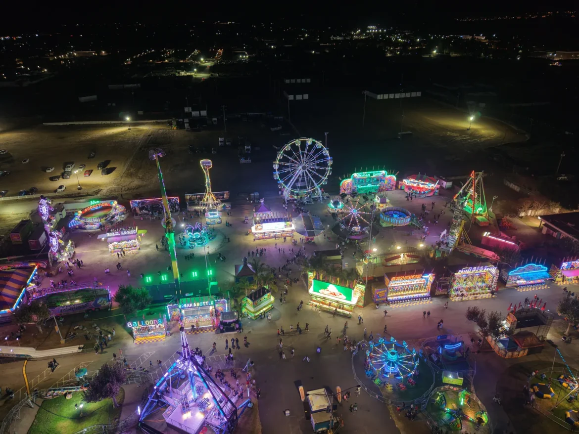 Aerial view of the carnival at night, rides glowing across the fairgrounds.