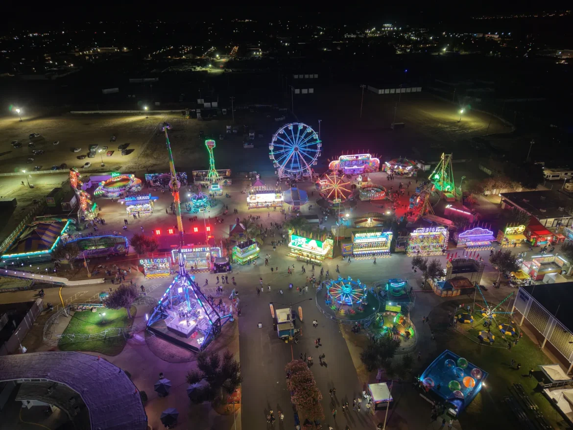 Aerial view of the Ferris wheel and midway lit up after dark.