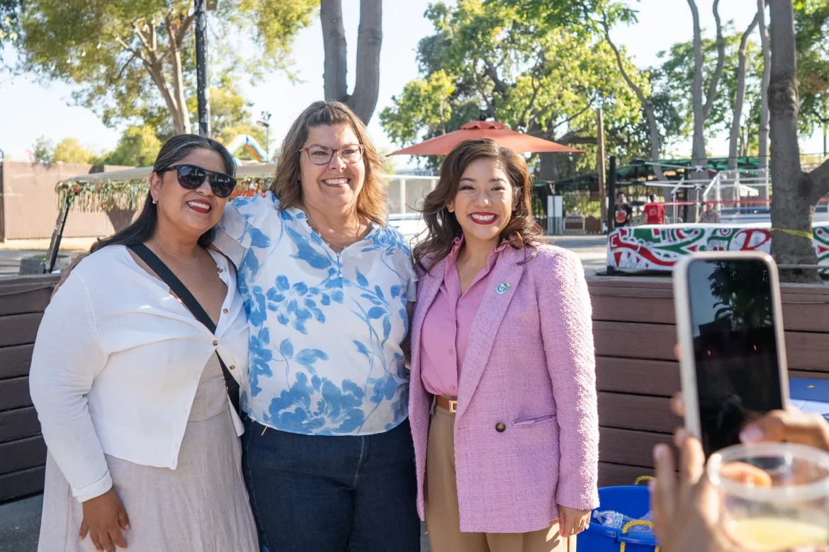Three fairgoers pose for a photo on a sunny afternoon.