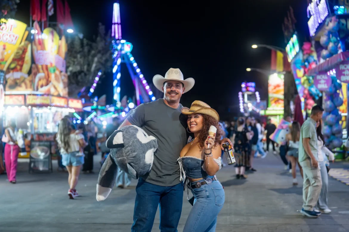 A couple walks the midway at night with a prize plush under one arm.